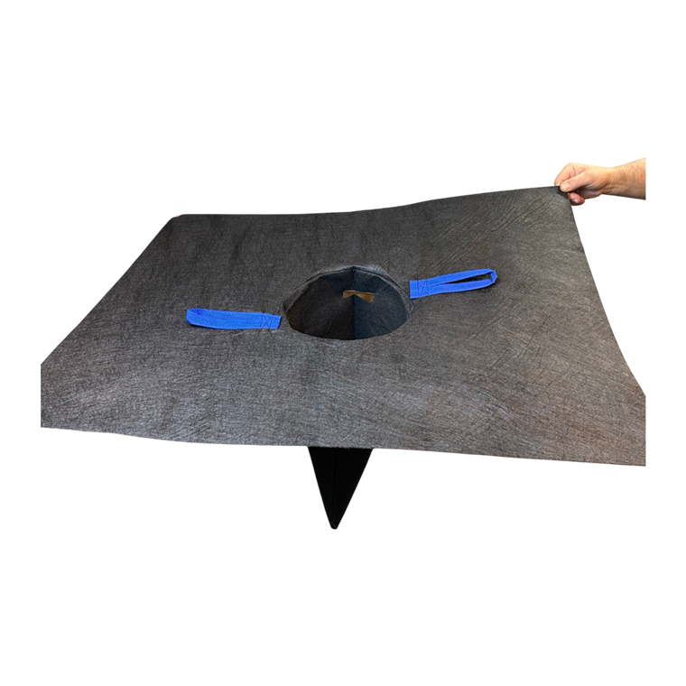 A hand holds a square, dark gray felt mat featuring a centered hole with a funnel-like extension and two blue tabs.