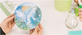 Hands hold a circular image of the Earth over a white desk with a lightbulb and notes, illustrating environmental study.