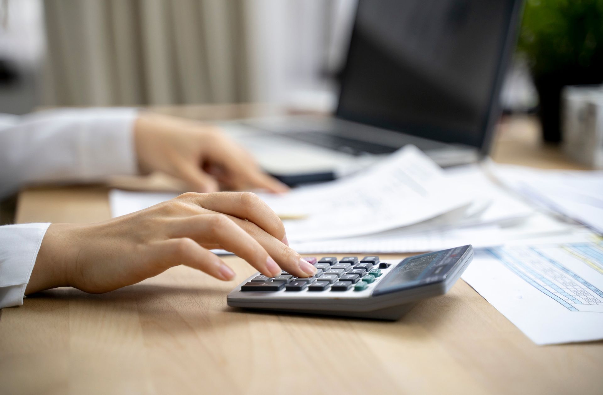 A woman is typing on a calculator.