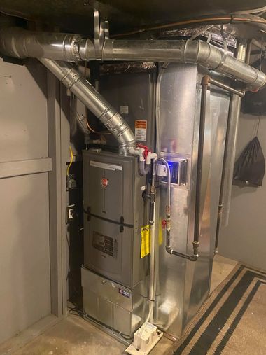 Industrial HVAC equipment with metal ductwork and insulated pipes in a utility room.
