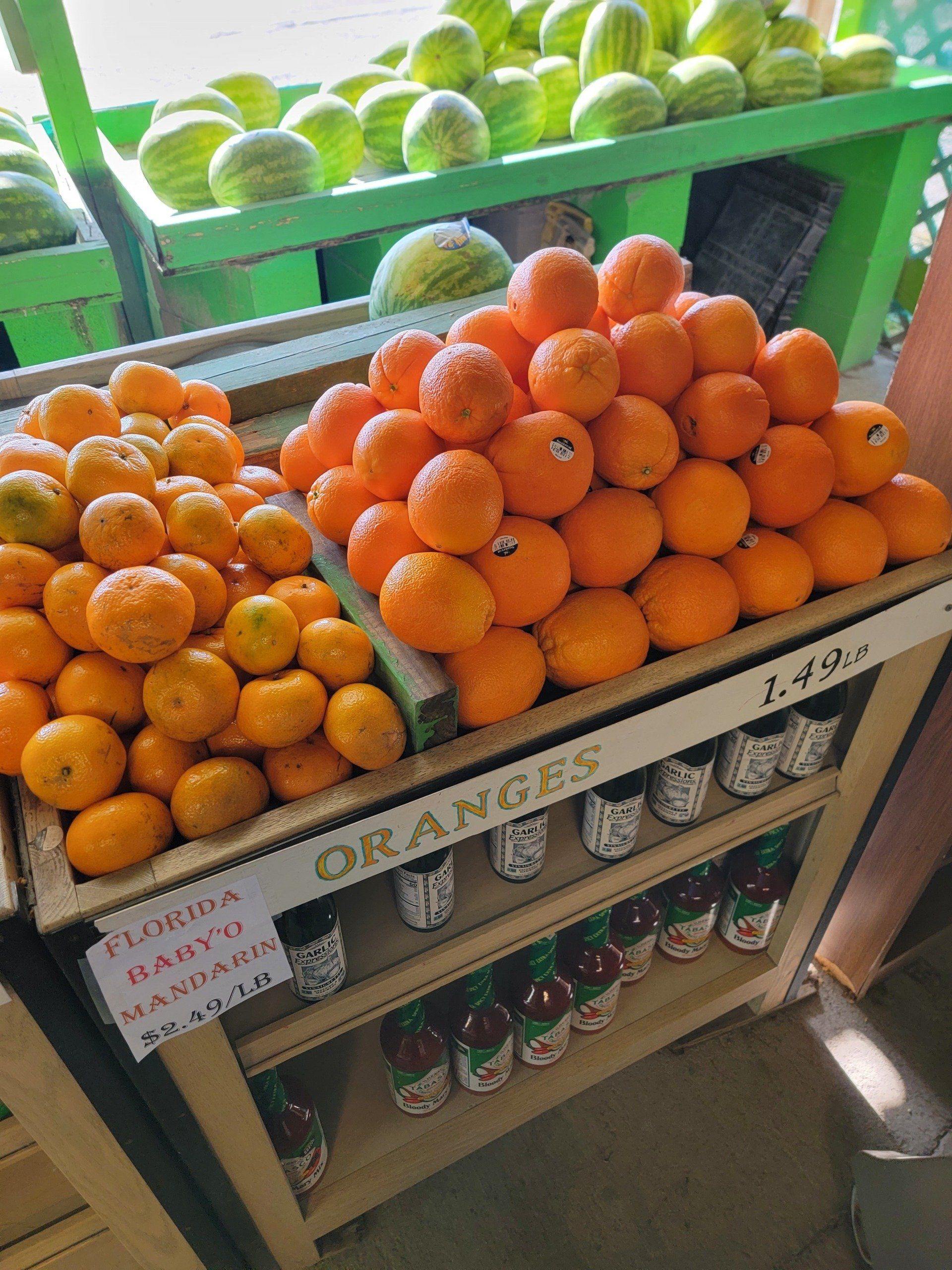 Oranges and tangerines stacked on a produce stand; price tag reads $1.49/lb.