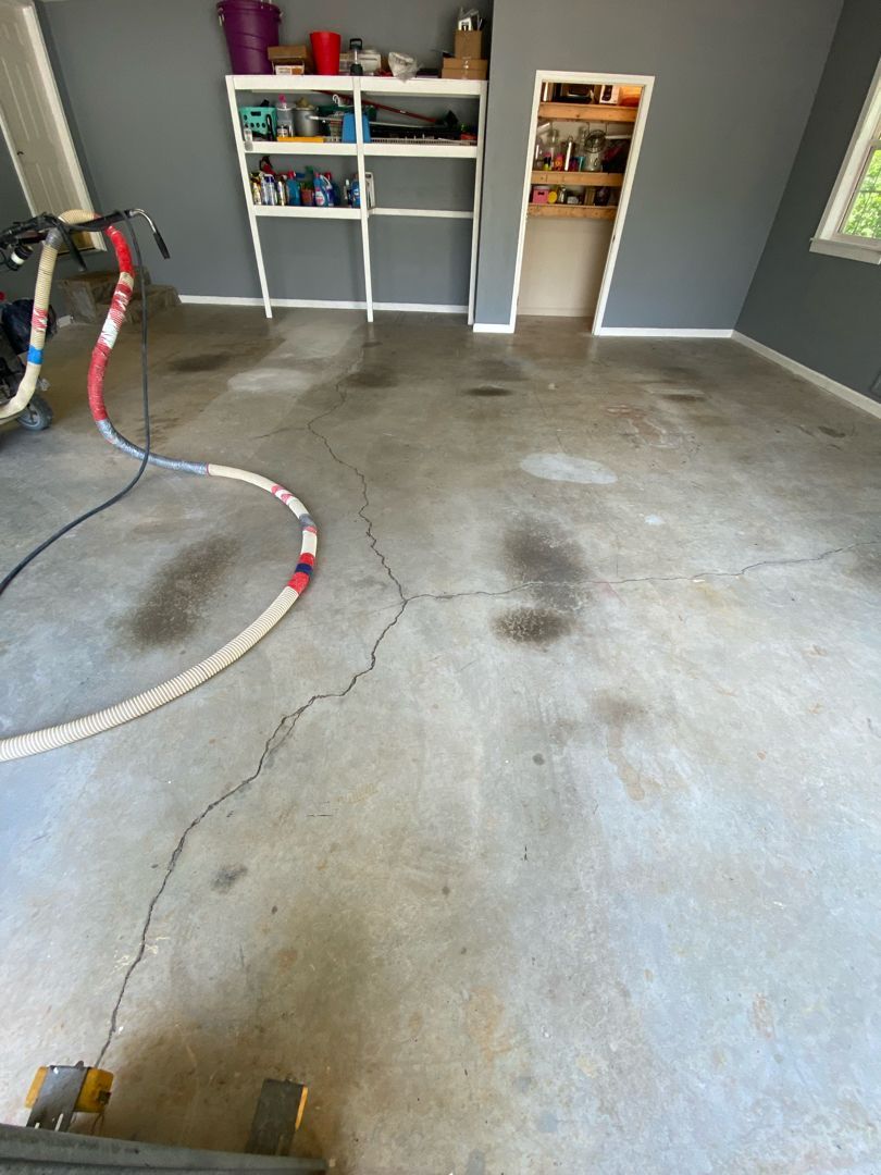 a dirty concrete floor in a garage with a vacuum cleaner .