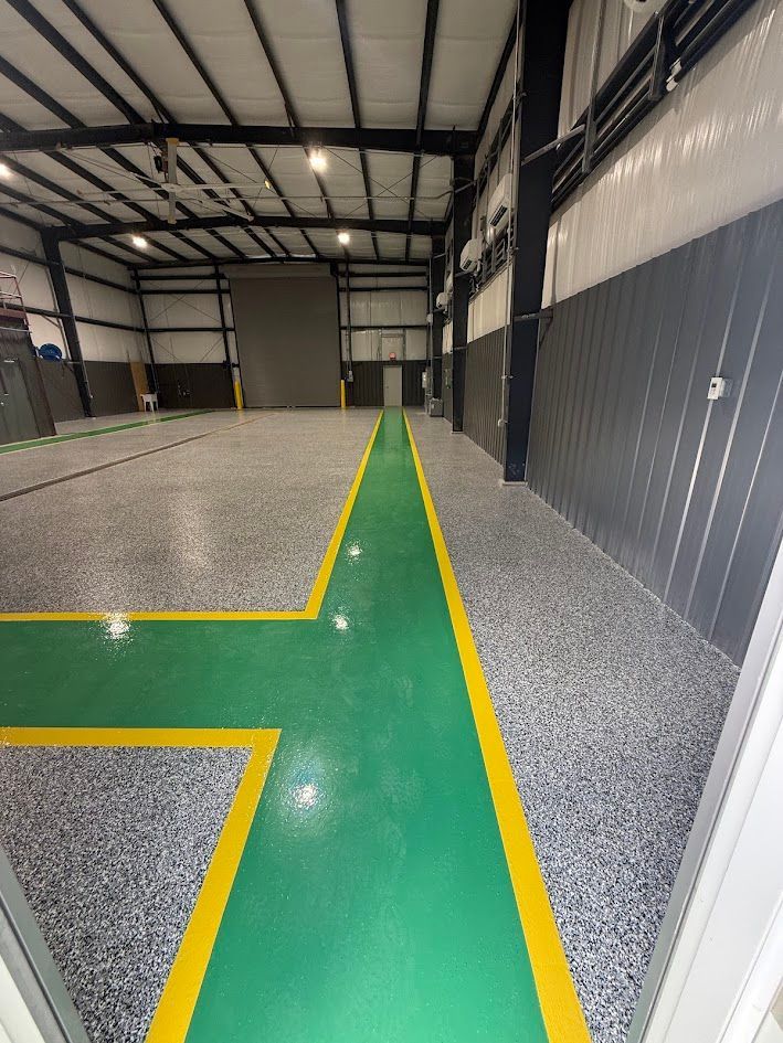 Interior of an industrial space with a green and yellow epoxy floor. Open doorway.
