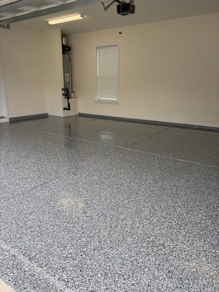 A freshly epoxy-coated garage floor with gray, black, and white flecks; off-white walls.