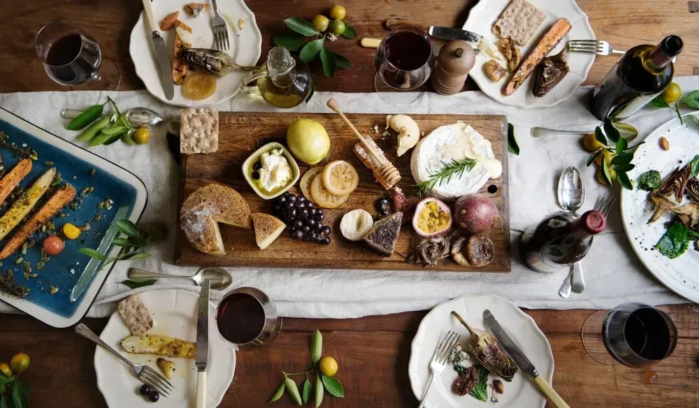A Wooden Table Topped With Plates of Food and Wine — The Larder Byron Bay in Byron Bay, NSW
