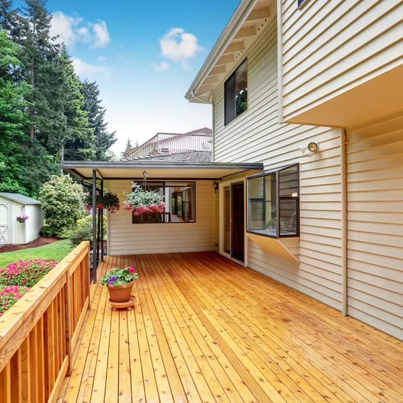 There is a large wooden deck in front of a house.