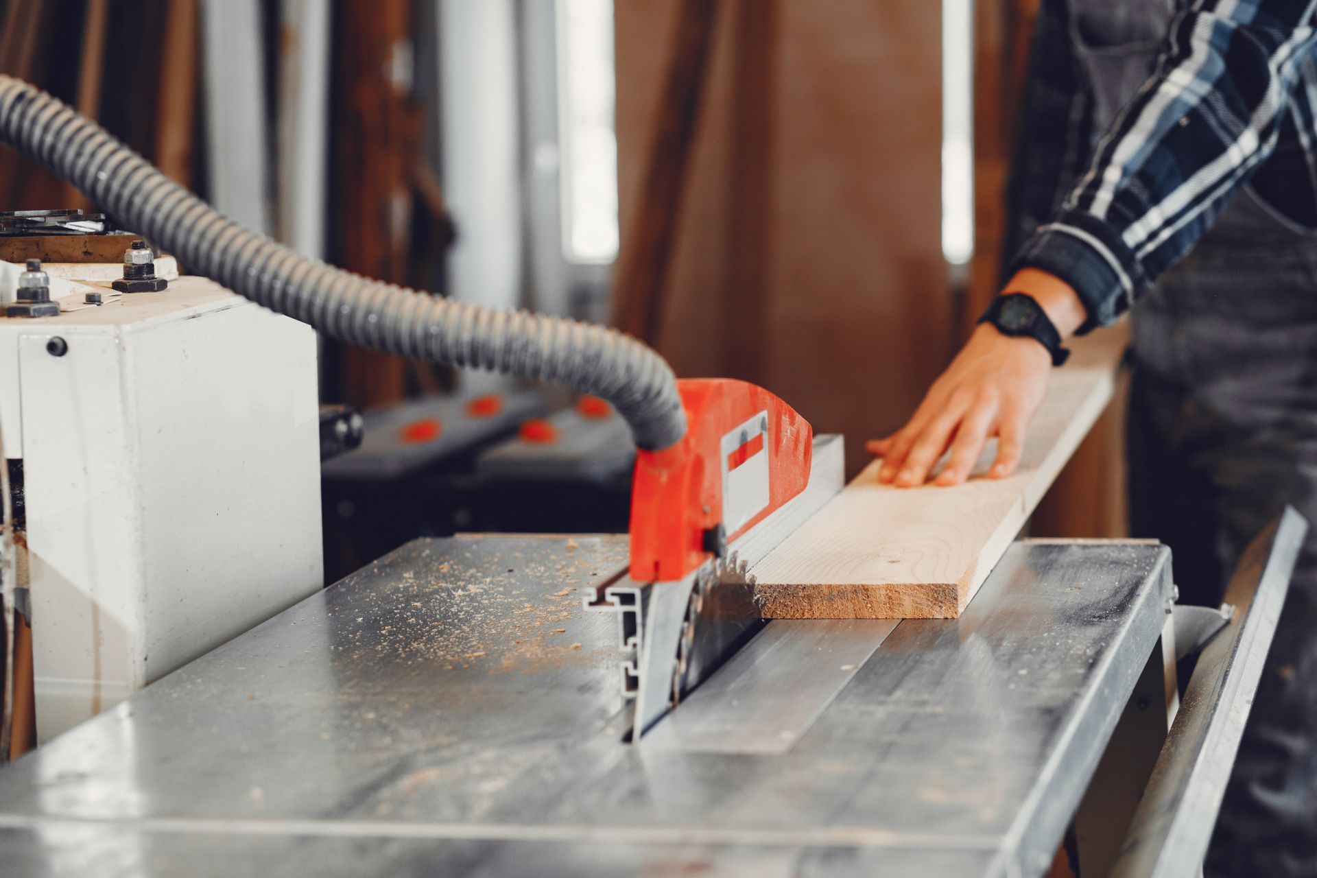 Person guiding wood through a table saw in a workshop