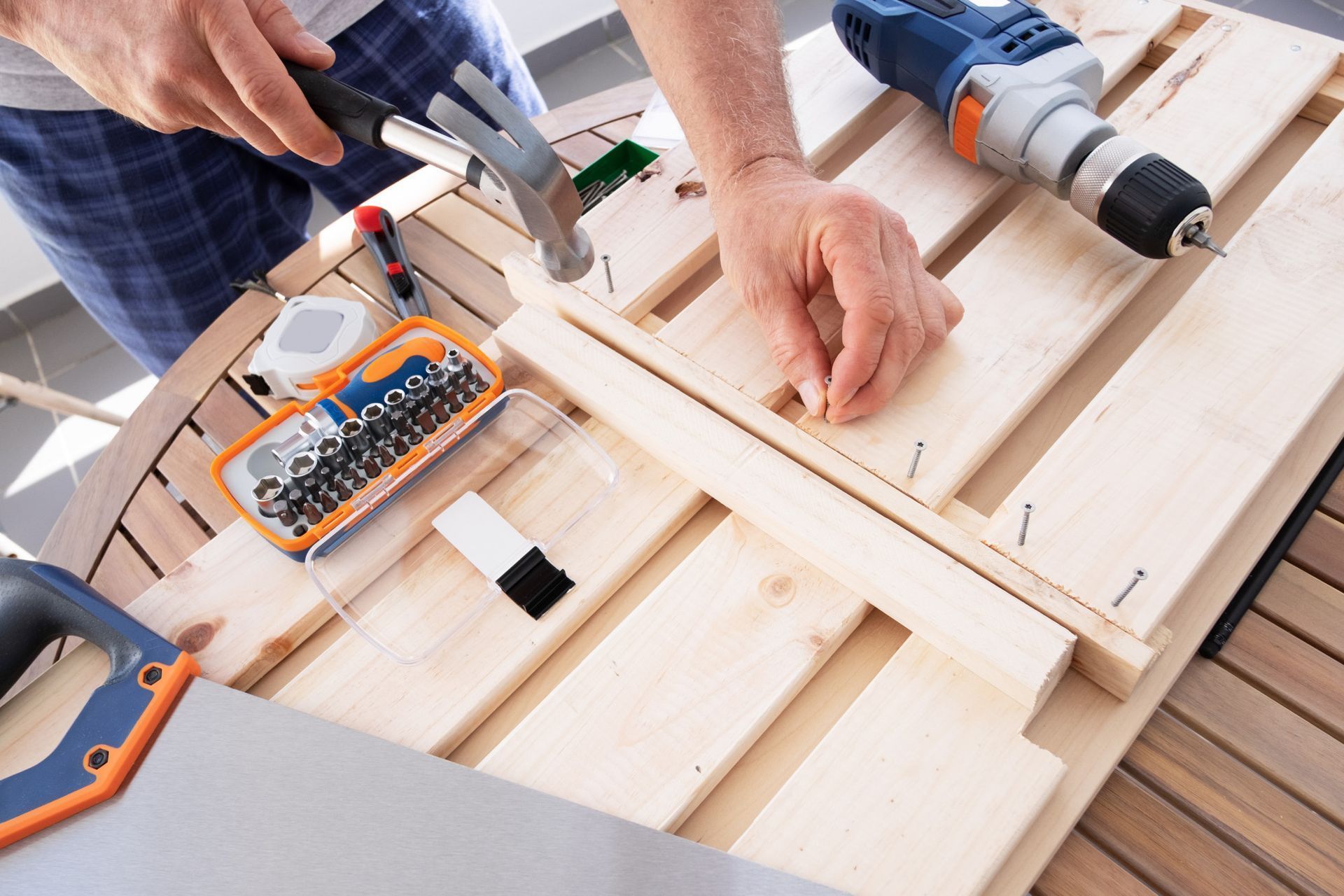 Hands using a cordless drill and clamps to build a wooden frame on a workbench