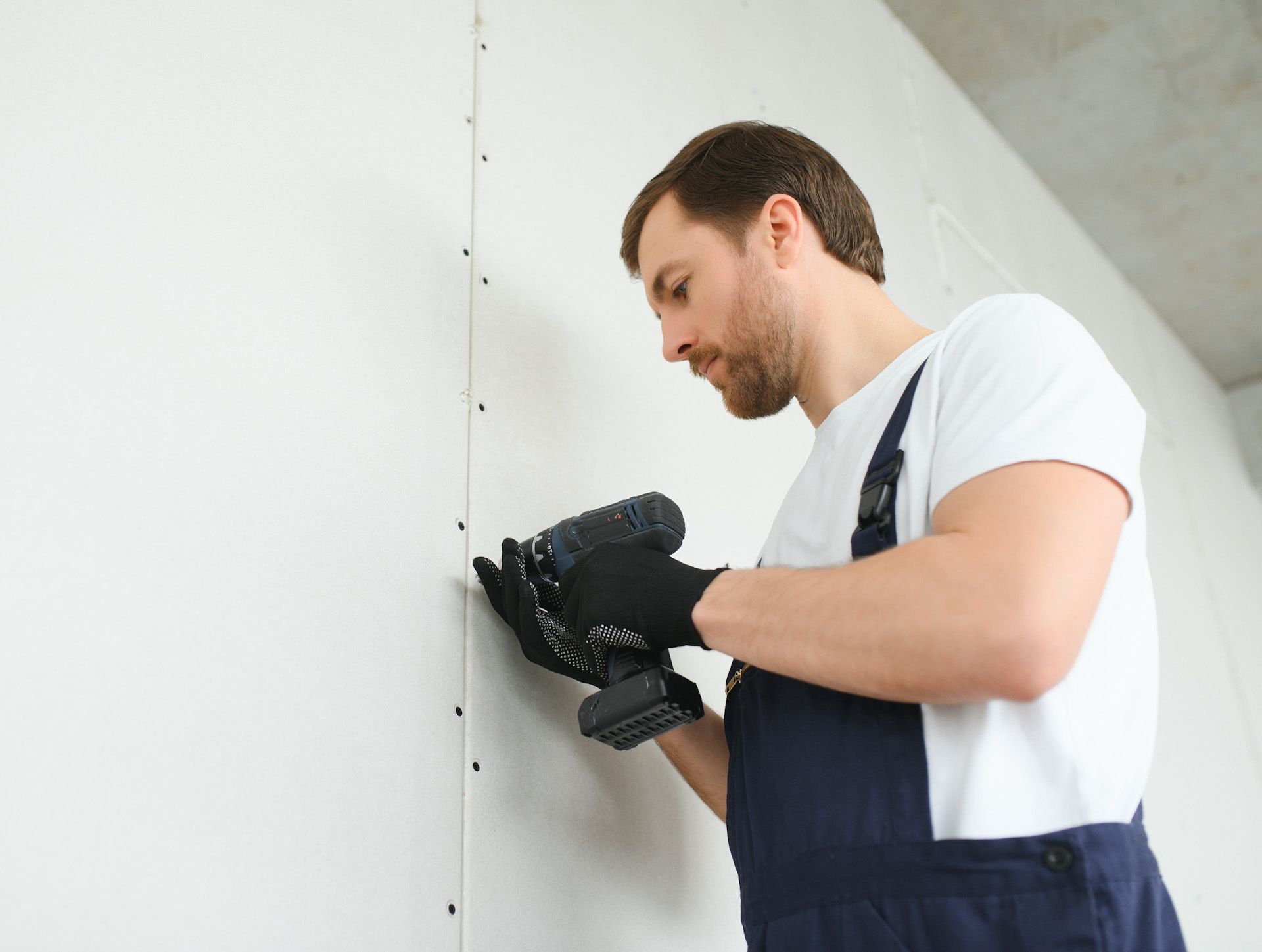 A man is using a drill on a wall.