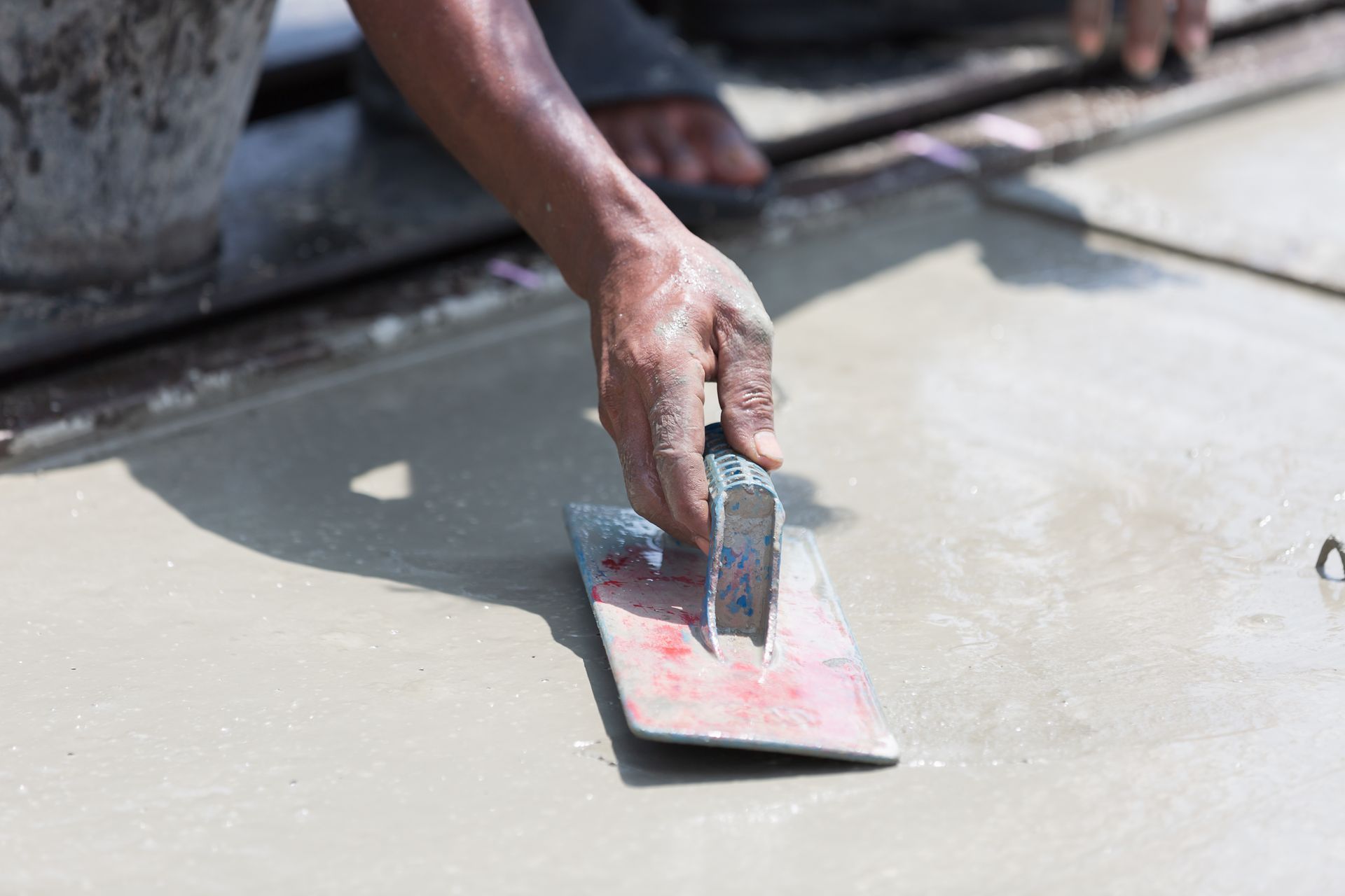 A close up of a person using a trowel on a concrete surface.