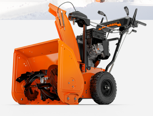Orange snowblower in front of a snowy background. The machine has a black engine, wheels, and control levers.