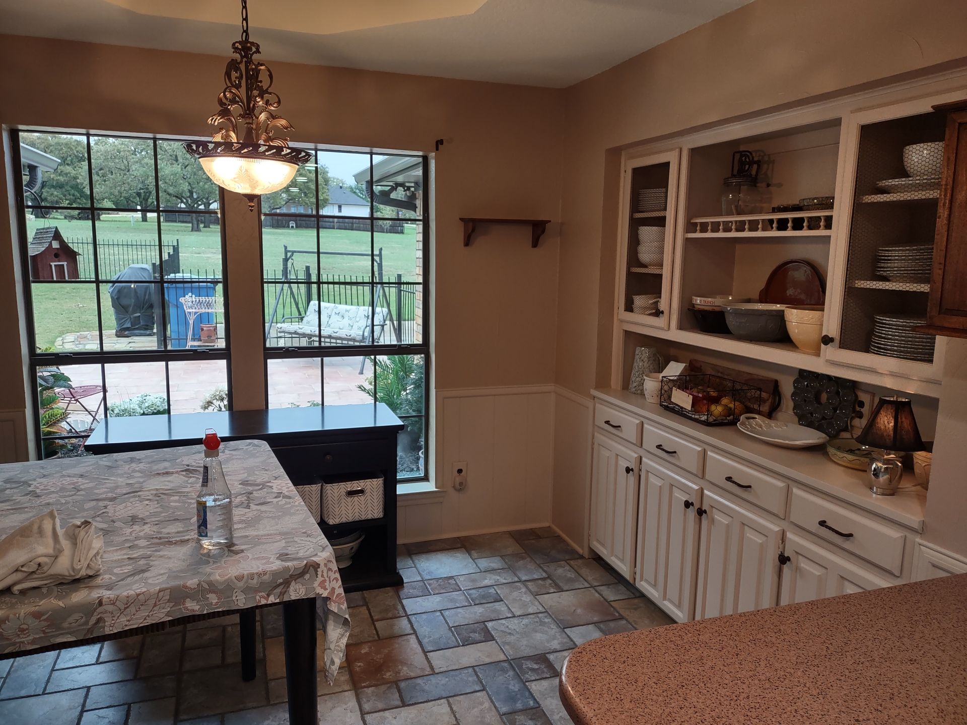 A kitchen with a table , cabinets , and a window.