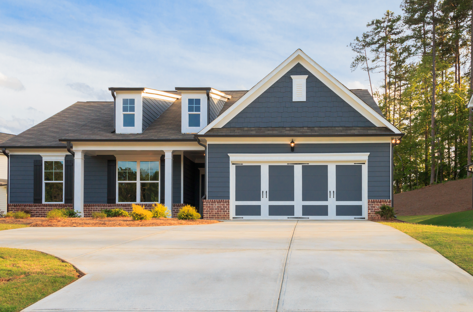 A large blue house with a concrete driveway in front of it.