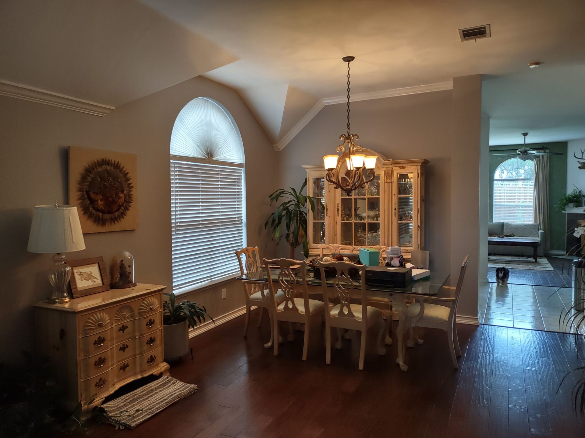 A dining room with a table and chairs and a chandelier hanging from the ceiling.