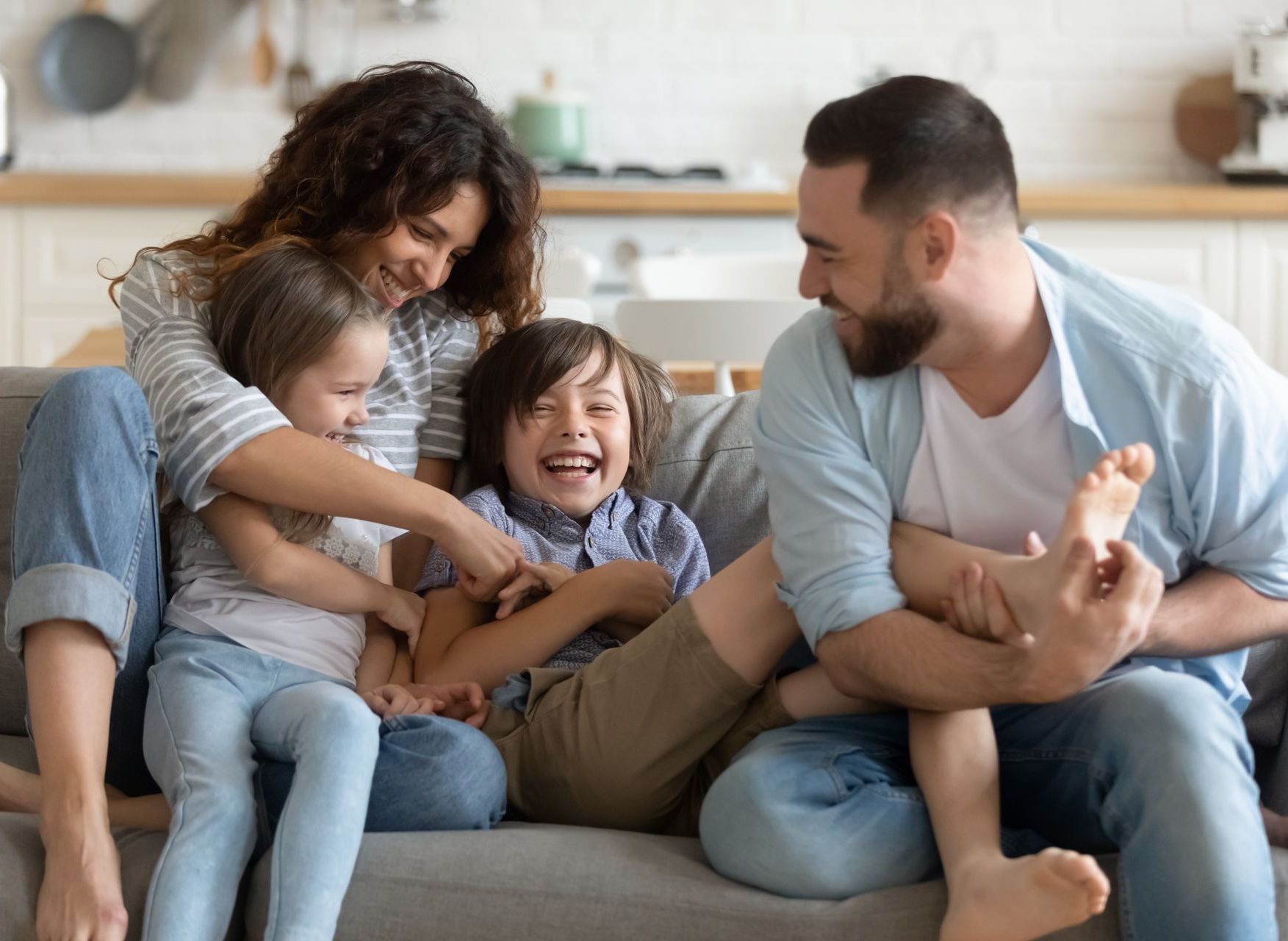 The couple cuddles and laughs with their children on the couch, showing the importance of date night with children