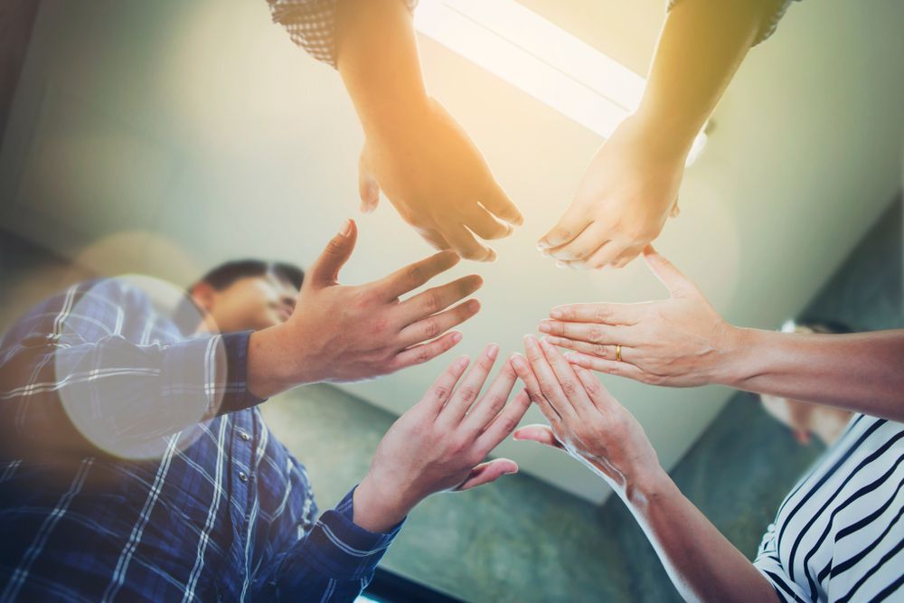 Several people hold their hands out to one another in prayer - What Is A Growth Mindset