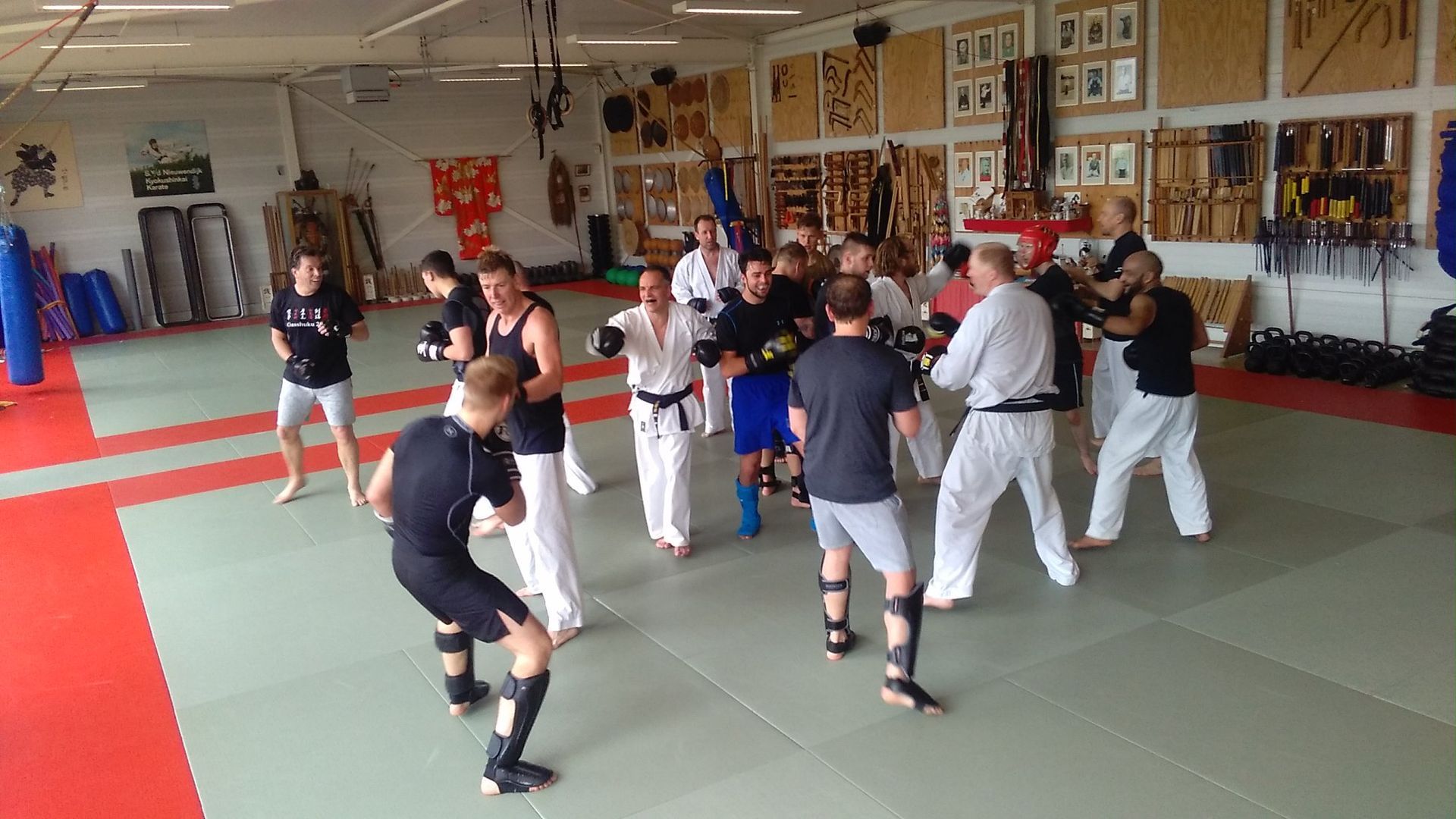 Een vechtsportles waarbij trappen worden geoefend en gespard op gewatteerde matten in sportschool van den nieuwendijk dojo.