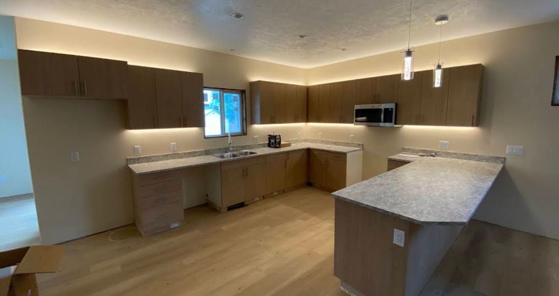 Modern empty kitchen with wood cabinets, light countertops, island, and wood flooring