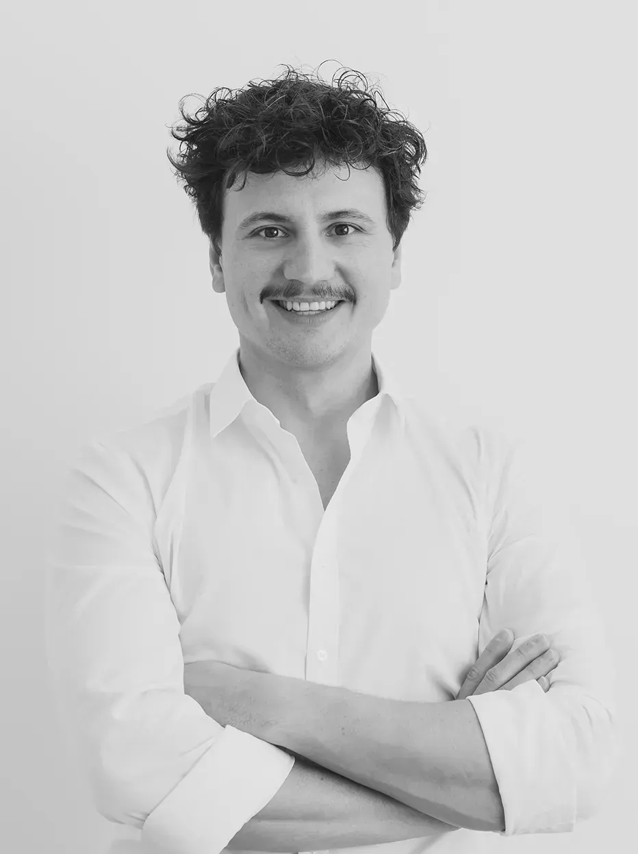 Ein Schwarzweißfoto eines Mannes in einem weißen Hemd mit verschränkten Armen.