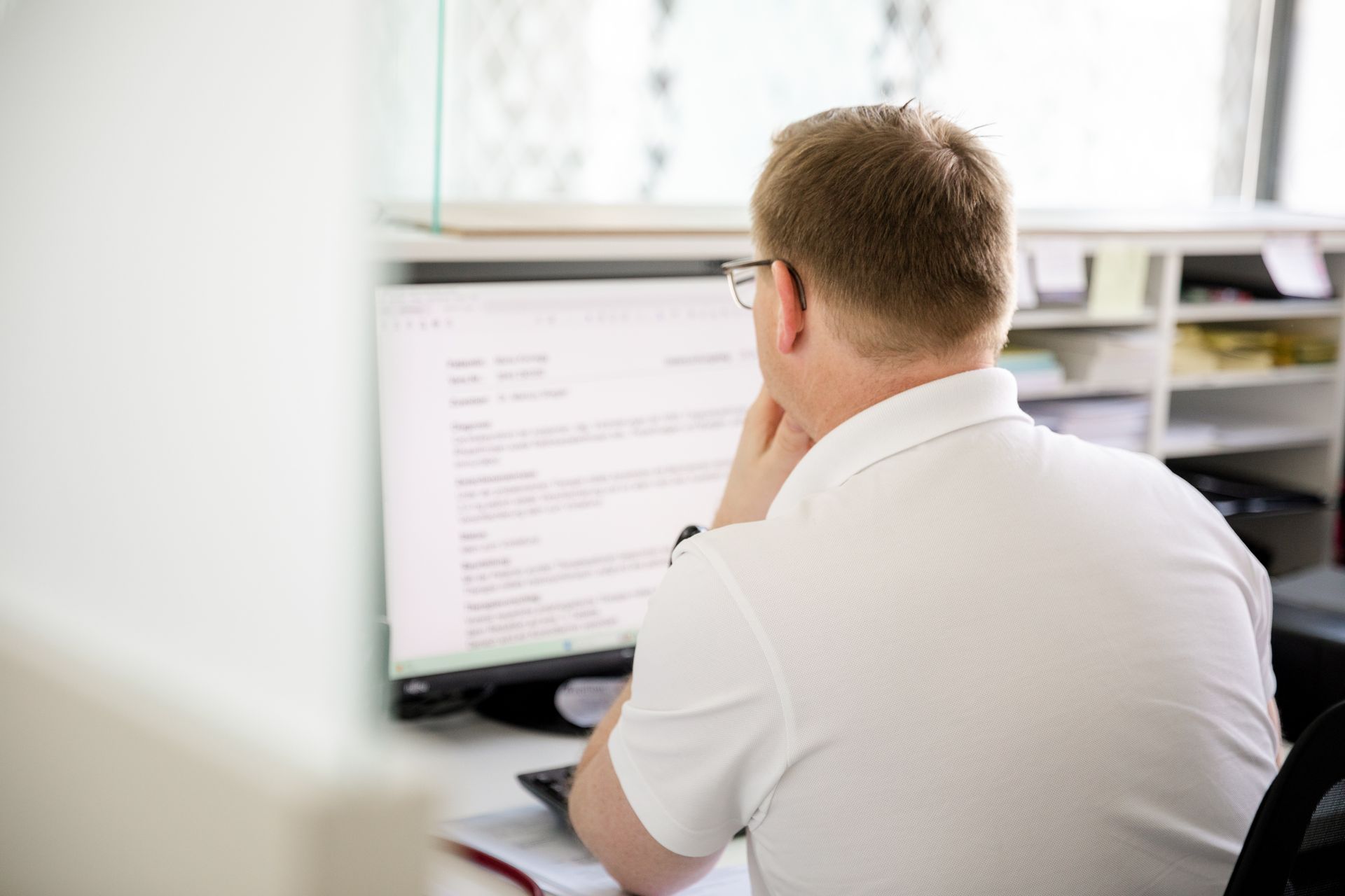 Ein Mann in einem weißen Hemd sitzt vor einem Computer.