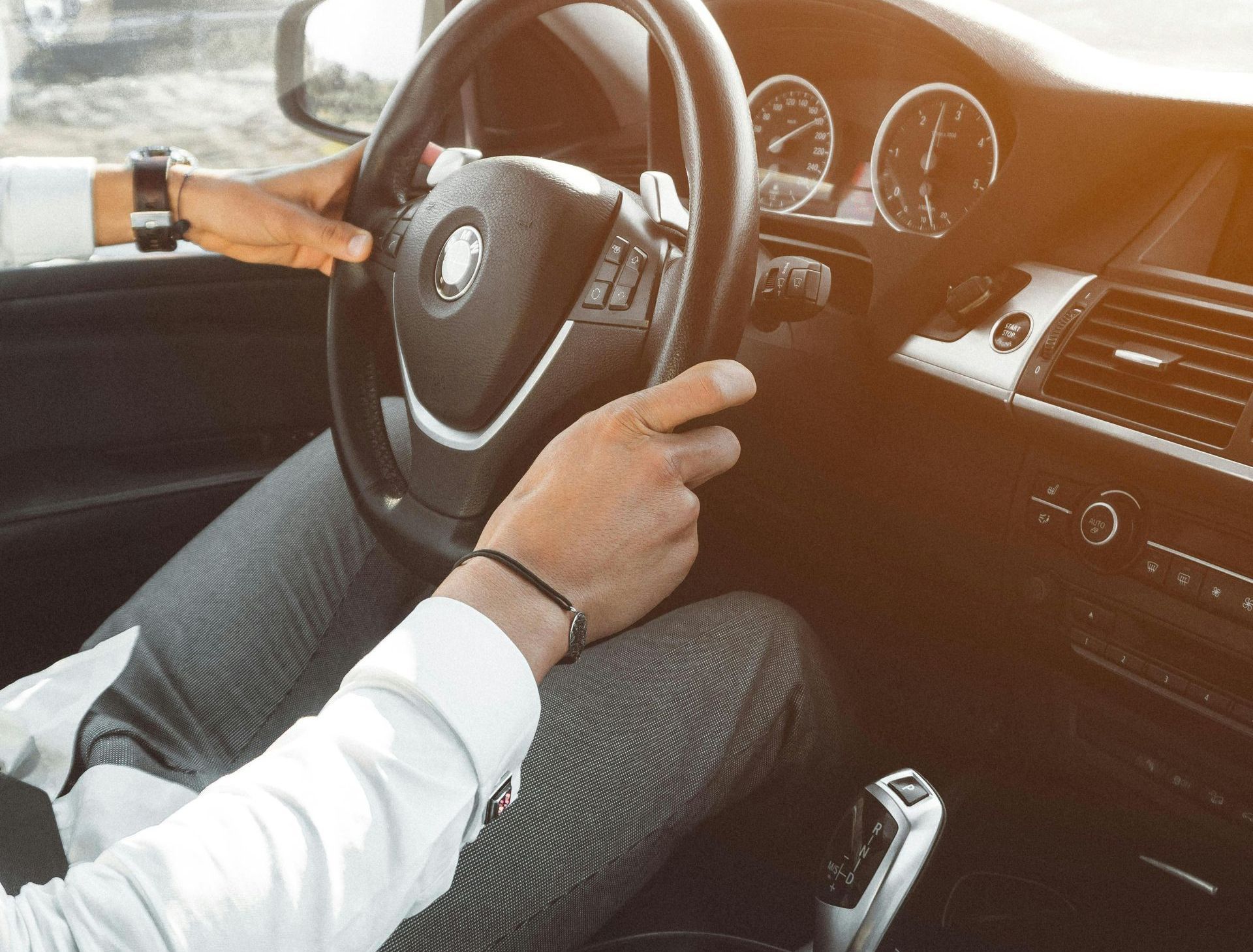 Ein Mann fährt Auto und hat die Hände am Lenkrad.