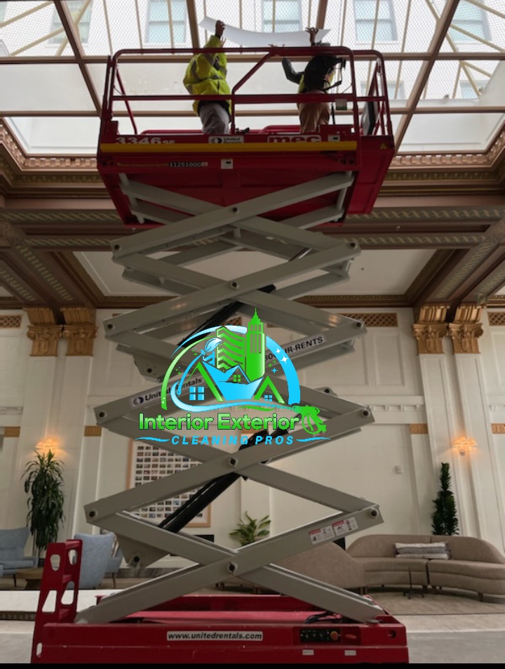 A man is standing on a scissor lift in a living room.