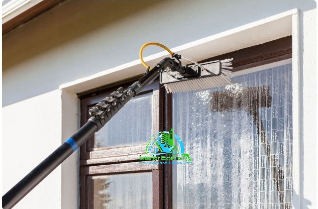 A window cleaner is cleaning a window with a long pole.