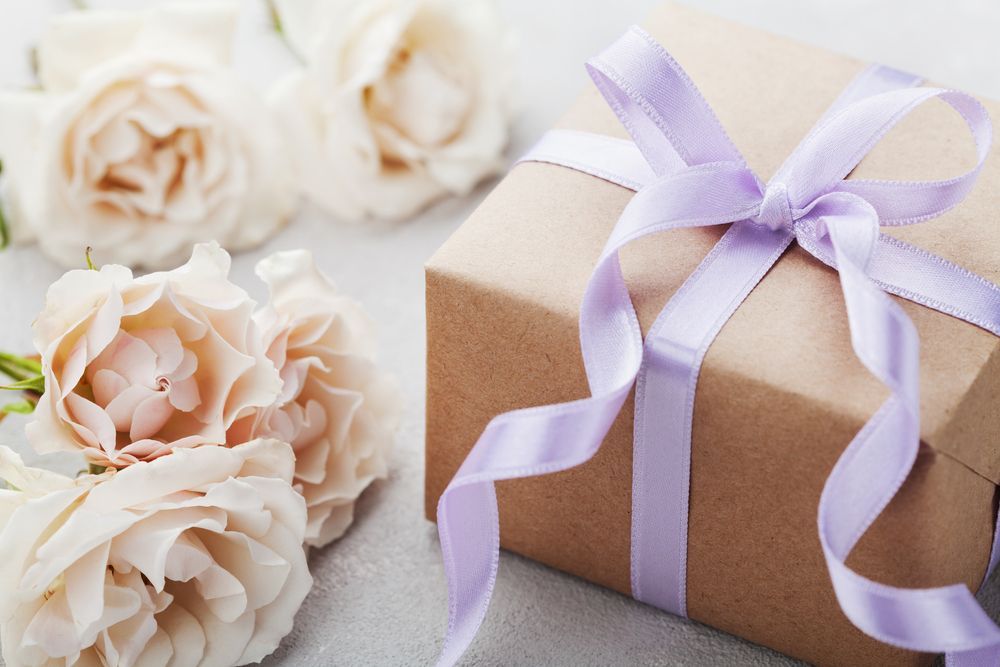 A Gift Box with A Purple Ribbon and Roses in The Background — Barnyard Stockfeed, Pet, Garden and Florist in Childers, QLD