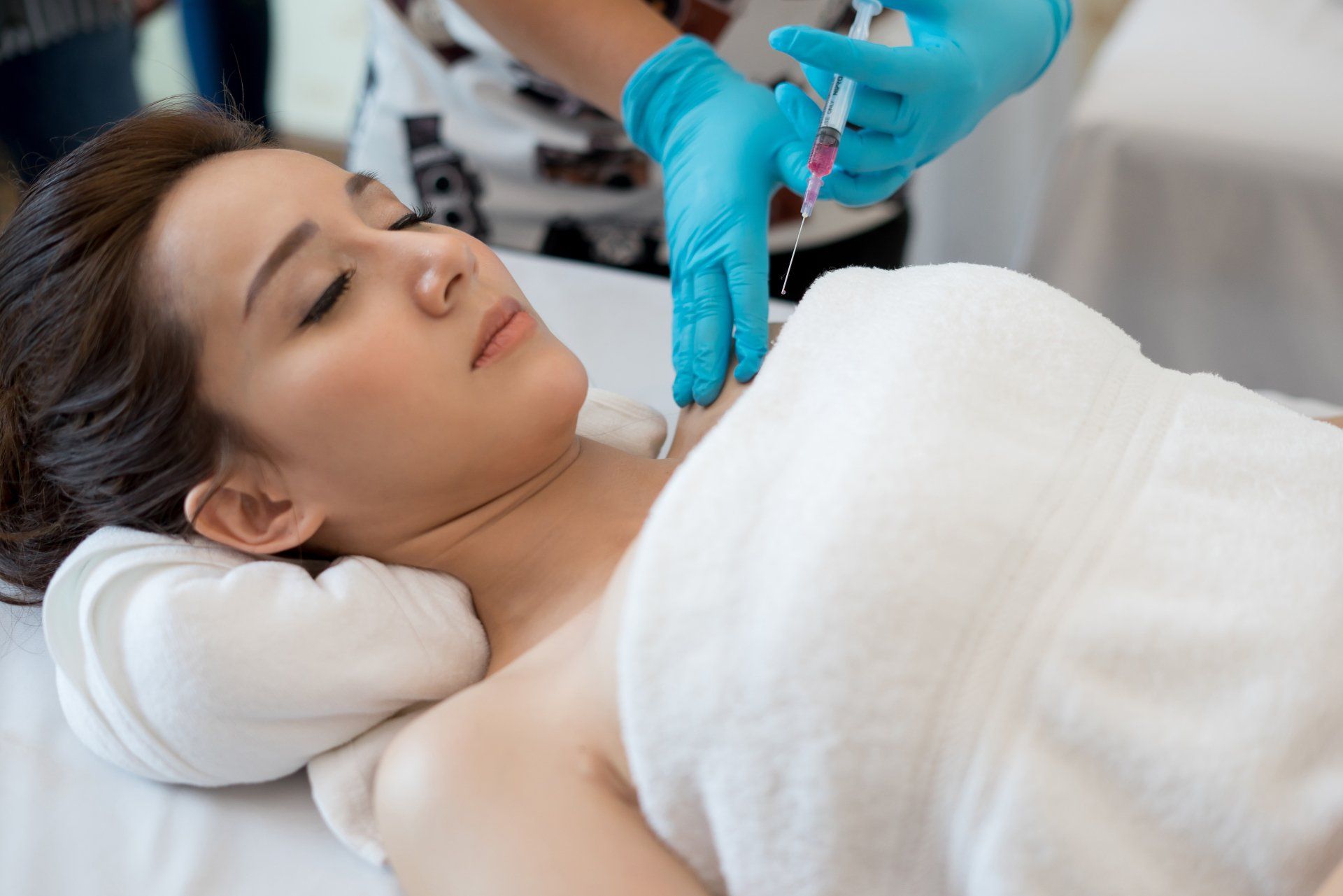 cosmotologist injecting a woman with botox on her shoulder