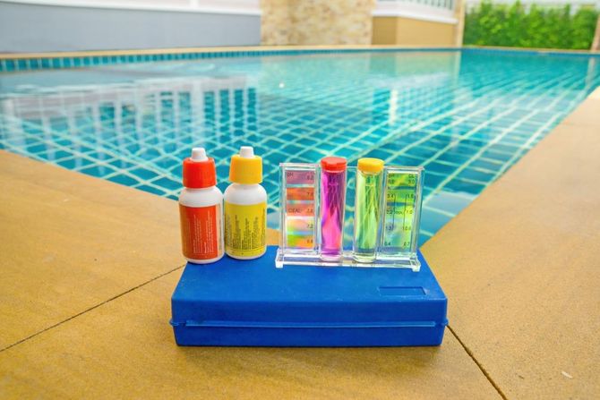 Poolside water testing kit with colorful test tubes and bottles on a blue tray