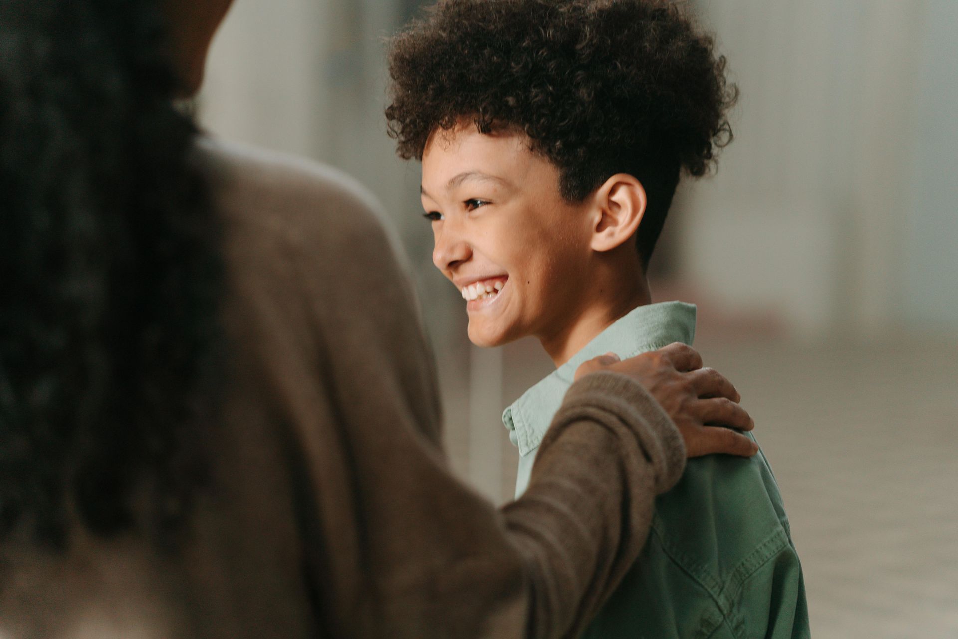 A woman is hugging a young boy who is smiling.