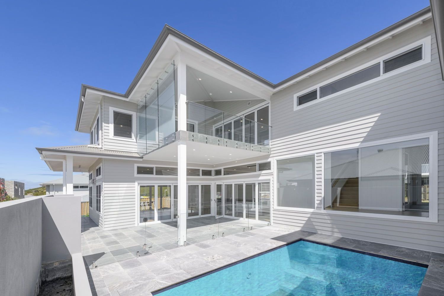 Two-story Modern Gray House With Glass Walls, Pool, and Outdoor Patio Under a Blue Sky — Indie Living In Lake Macquarie, NSW