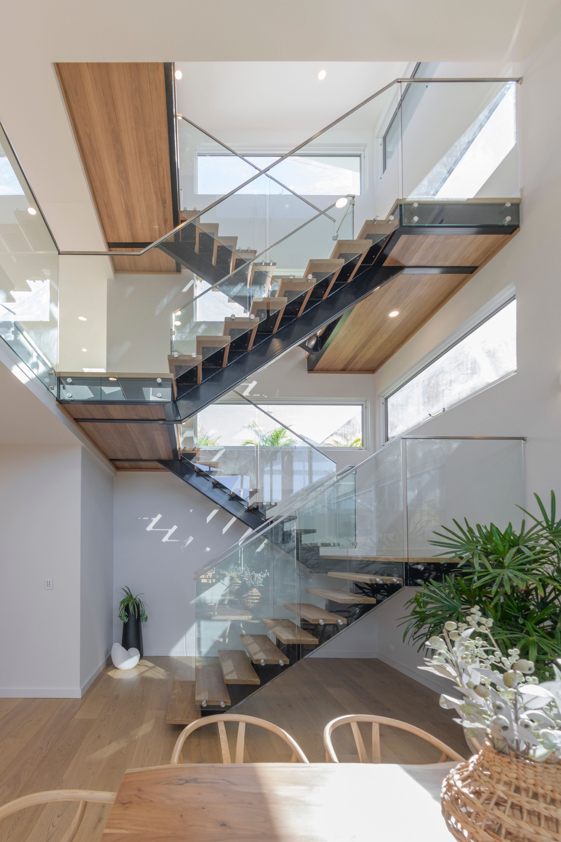 Wooden staircase with glass railings, sunlight, modern interior — Indie Living In Bennetts Green, NSW