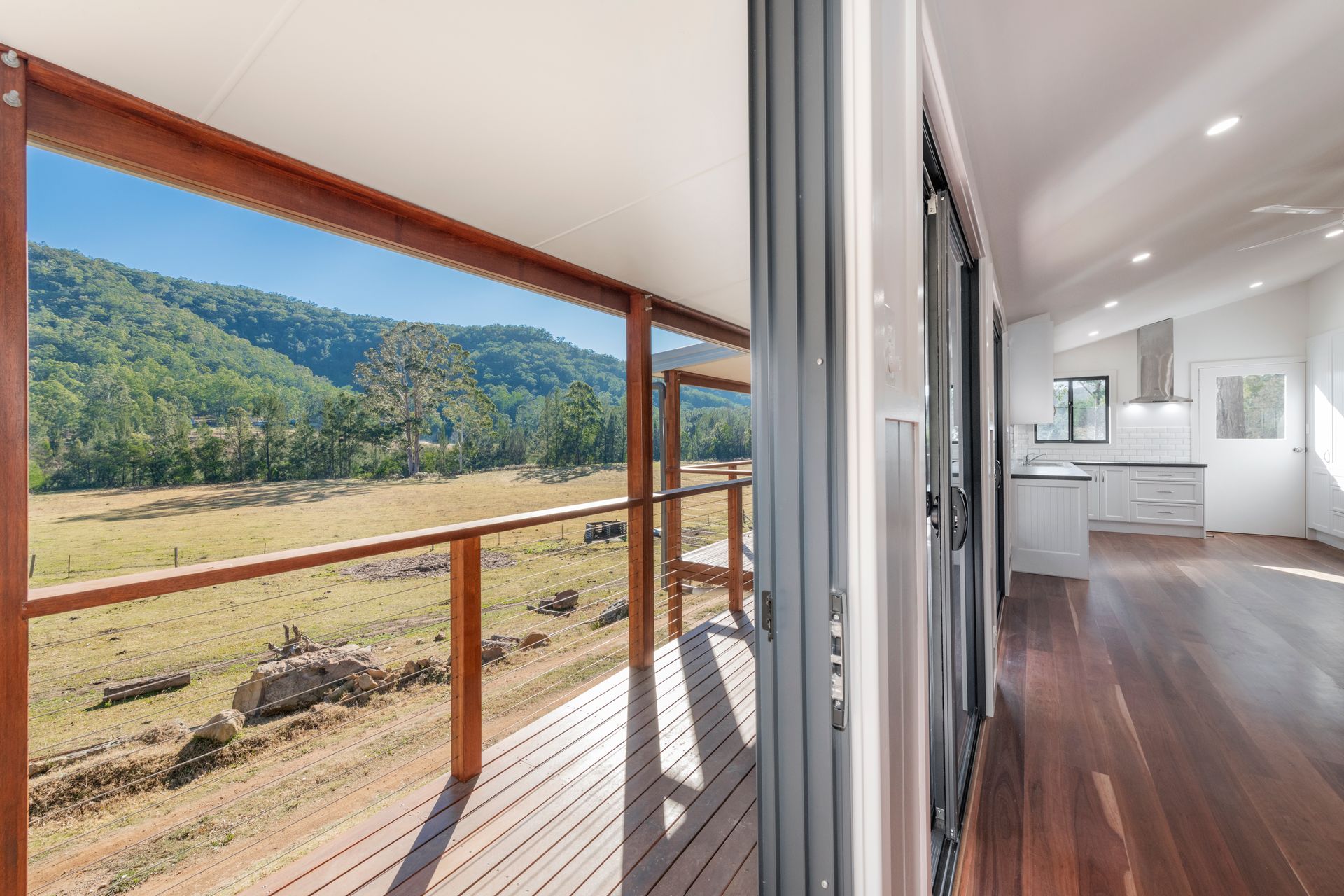 Wooden deck with mountain view; interior with kitchen and sliding doors — Indie Living In Hunter Valley, NSW