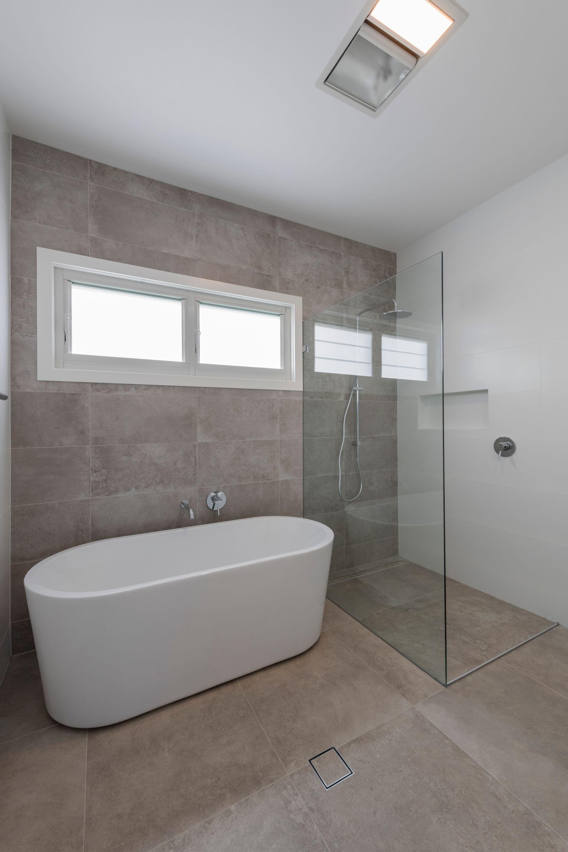 Modern Bathroom With a White Tub, Glass Shower, and Grey Tile Walls — Indie Living In Lake Macquarie, NSW