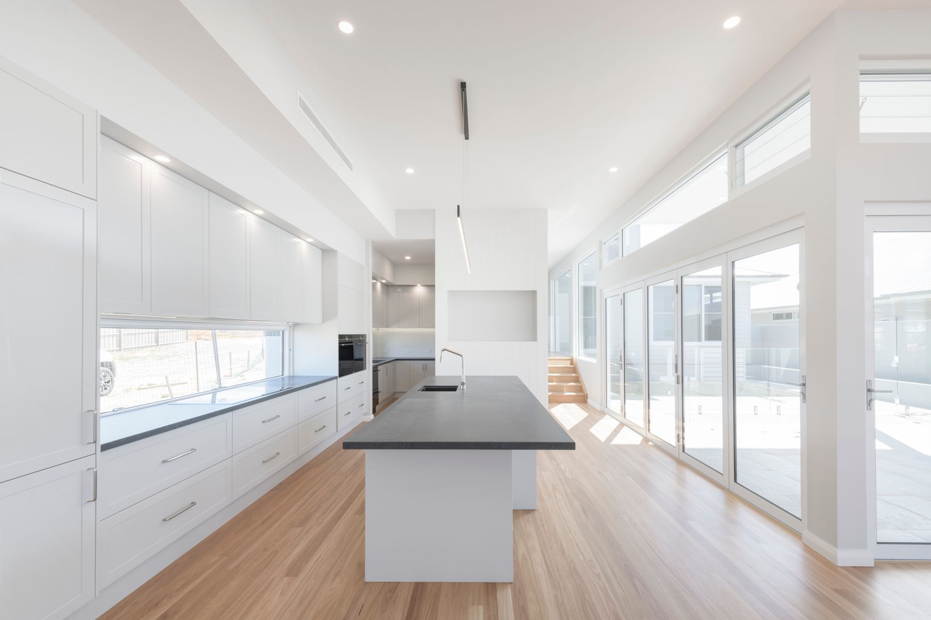 Modern, Bright Kitchen With White Cabinets, Wooden Floors, and Large Windows — Indie Living In Lake Macquarie, NSW