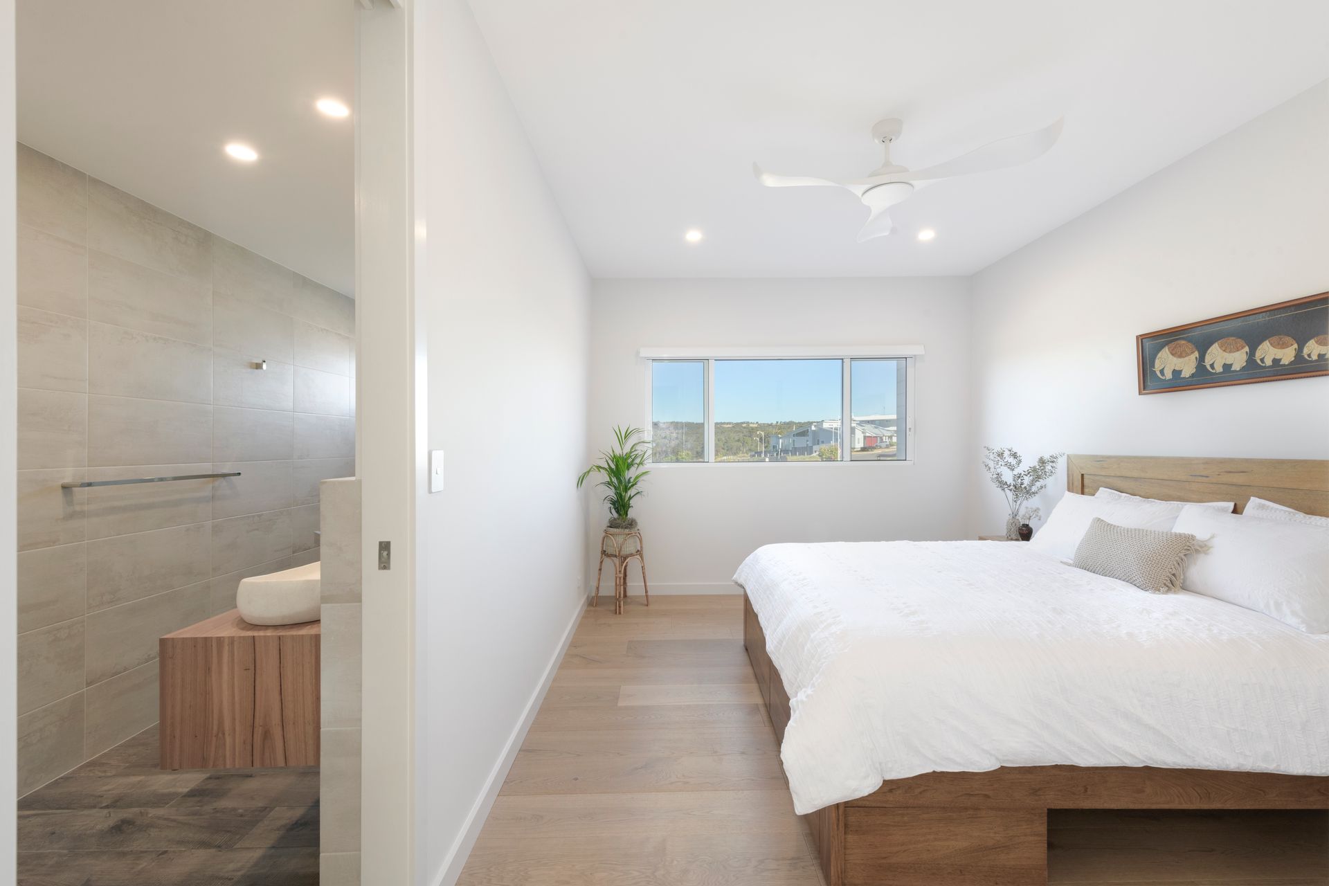 Bedroom with a bed, window, and ensuite bathroom. Light wood floors and white walls — Indie Living In Bennetts Green, NSW