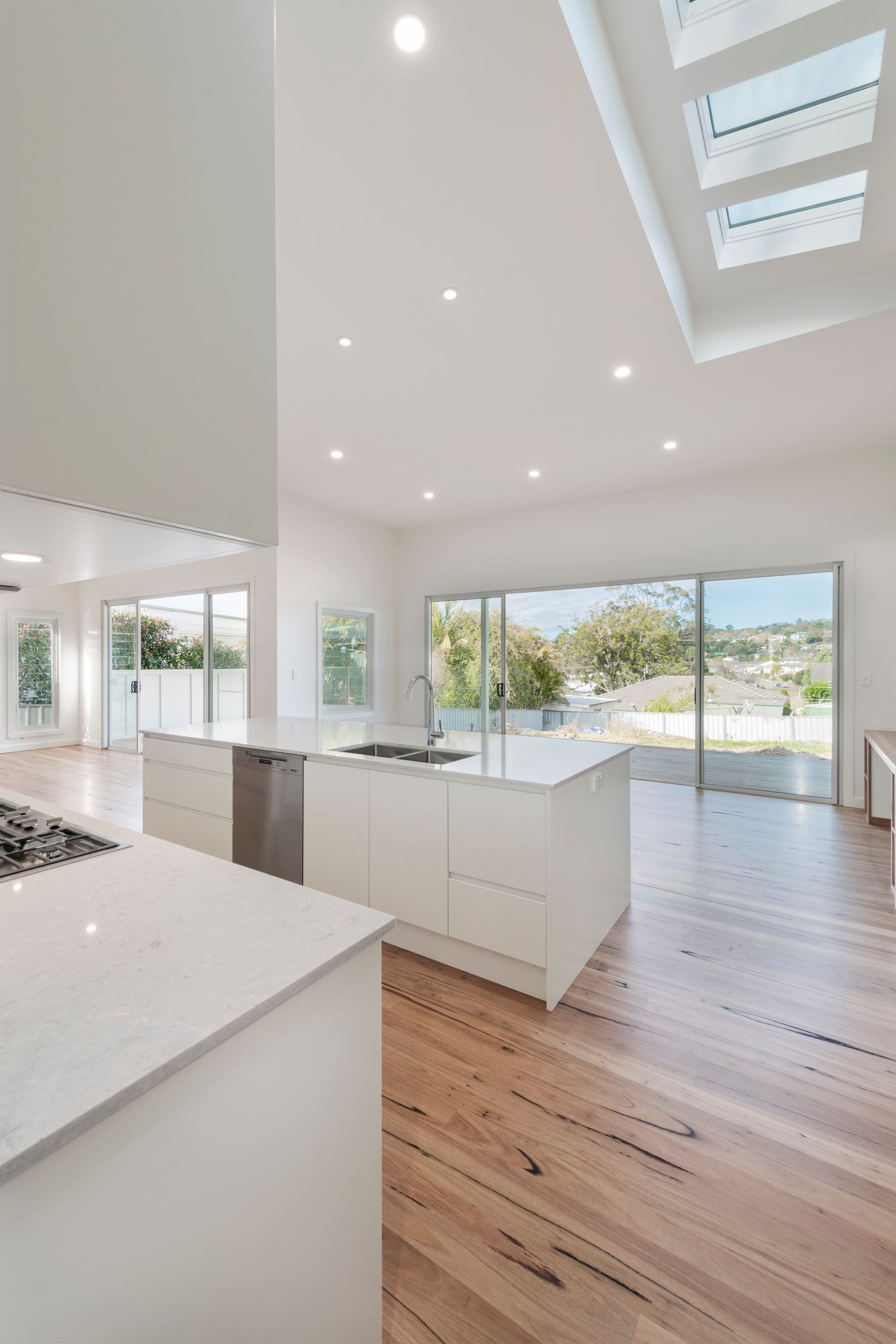 Bright Modern Kitchen With White Island, Wood Floors, and Sliding Glass Doors — Indie Living In Lake Macquarie, NSW
