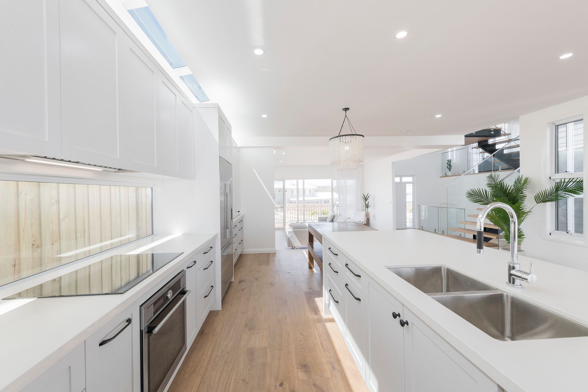 Bright, white kitchen with long island and cabinetry. Hardwood floors and skylight — Indie Living In Bennetts Green, NSW
