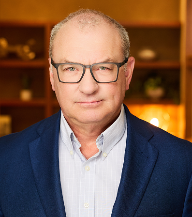 Man with glasses in blue blazer, indoors.