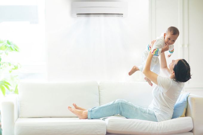 A woman is laying on a couch holding a baby in the air.