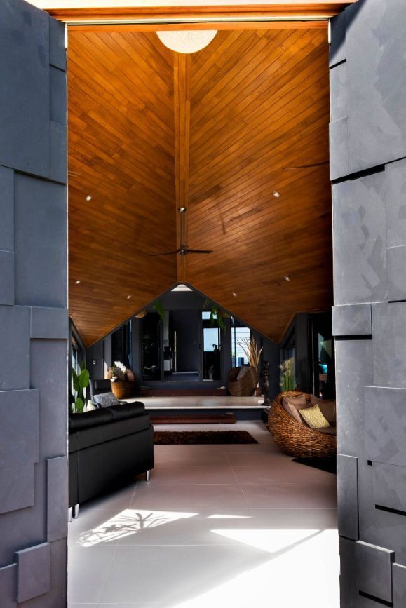 A Living Room With a Wooden Ceiling and a Black Couch — Omni Builders In Bungalow, QLD