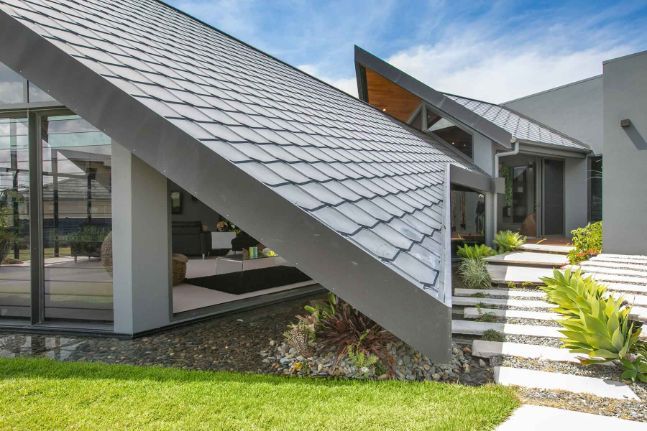 A Modern House With a Curved Roof and Stairs Leading to It — Omni Builders In Bungalow, QLD
