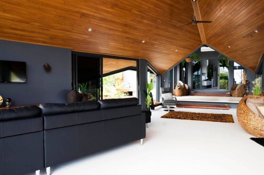 A Living Room With a Wooden Ceiling and a Black Couch — Omni Builders In Bungalow, QLD
