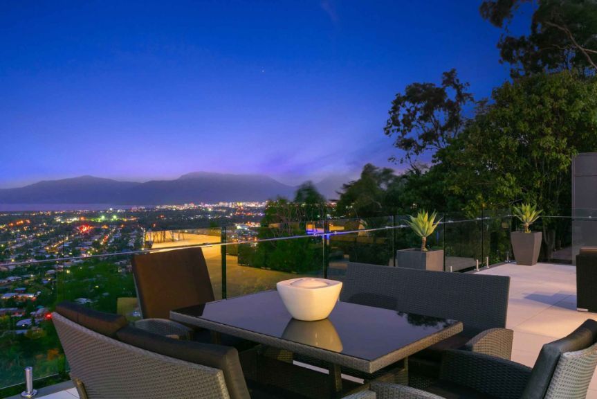 A Patio With a Table and Chairs and a View of a City at Night — Omni Builders In Bungalow, QLD