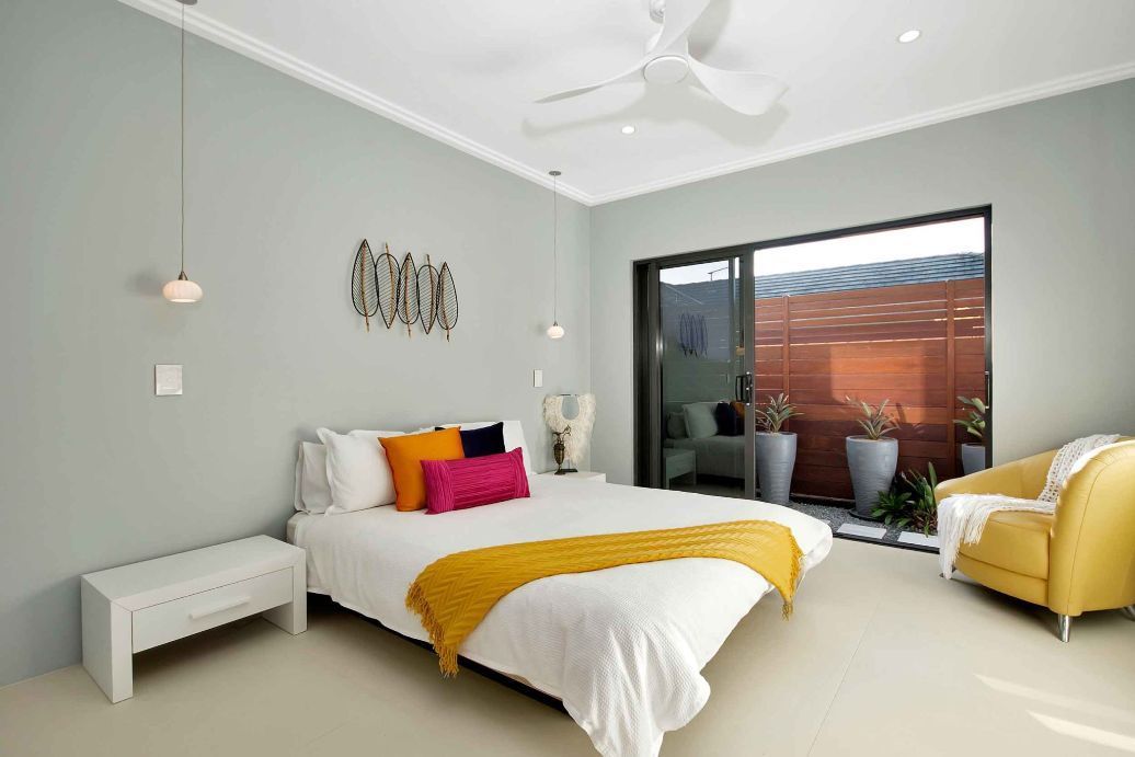 A Bedroom With a Large Bed and a Yellow Chair — Omni Builders In Bungalow, QLD