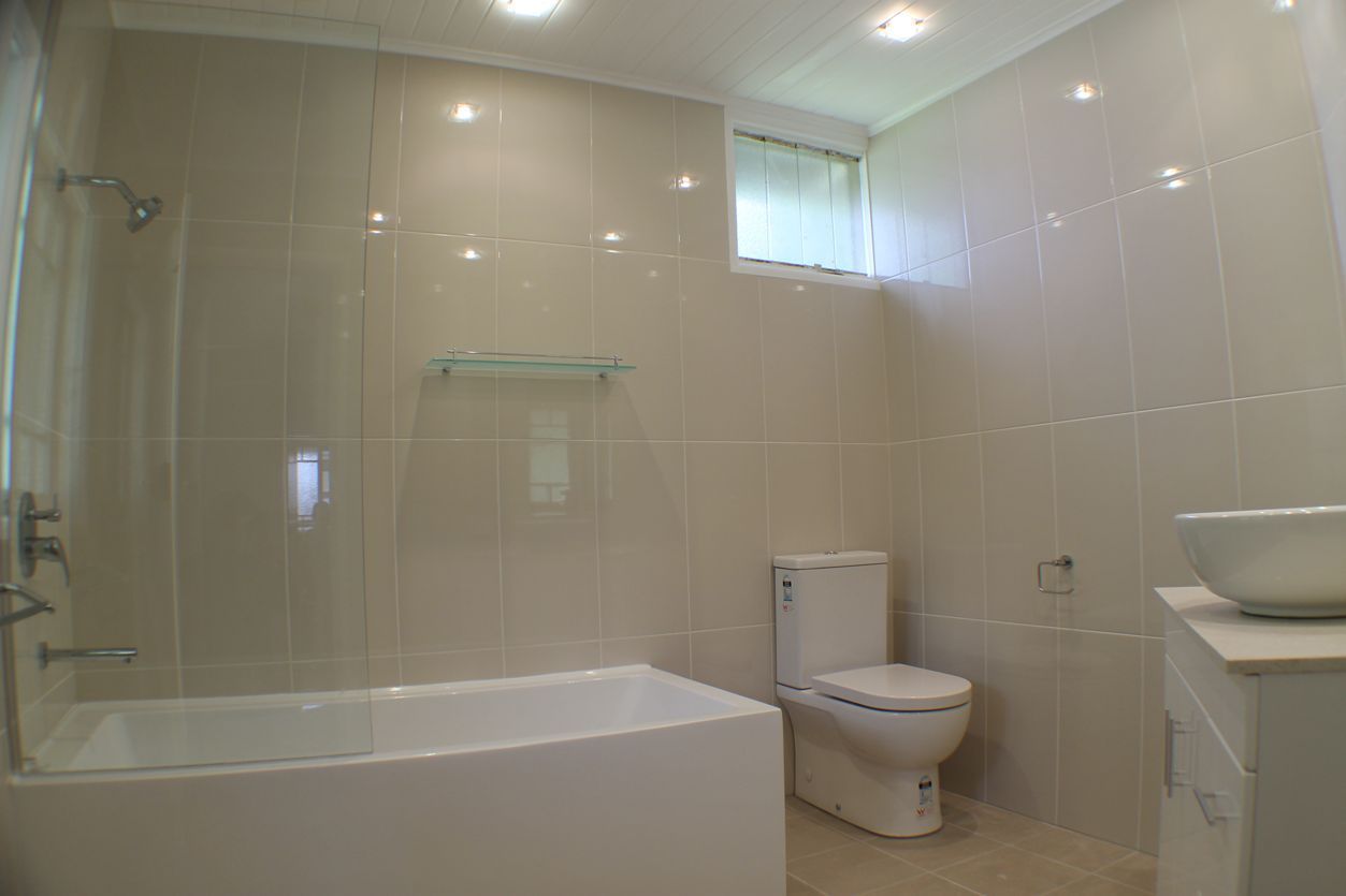 A Bathroom With a Toilet , Sink , Bathtub and Shower — Omni Builders In Bungalow, QLD