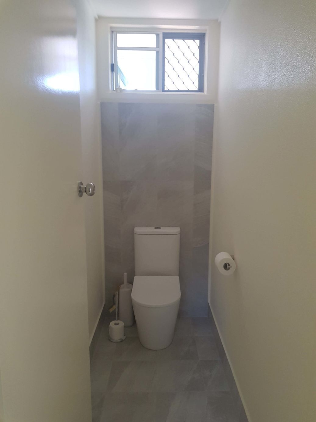 A Bathroom With a Toilet , Paper Towels , and a Window — Omni Builders In Bungalow, QLD