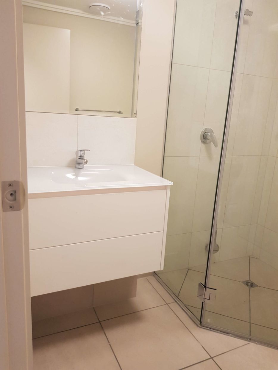 A Bathroom With a Sink , Mirror and Shower Stall — Omni Builders In Bungalow, QLD