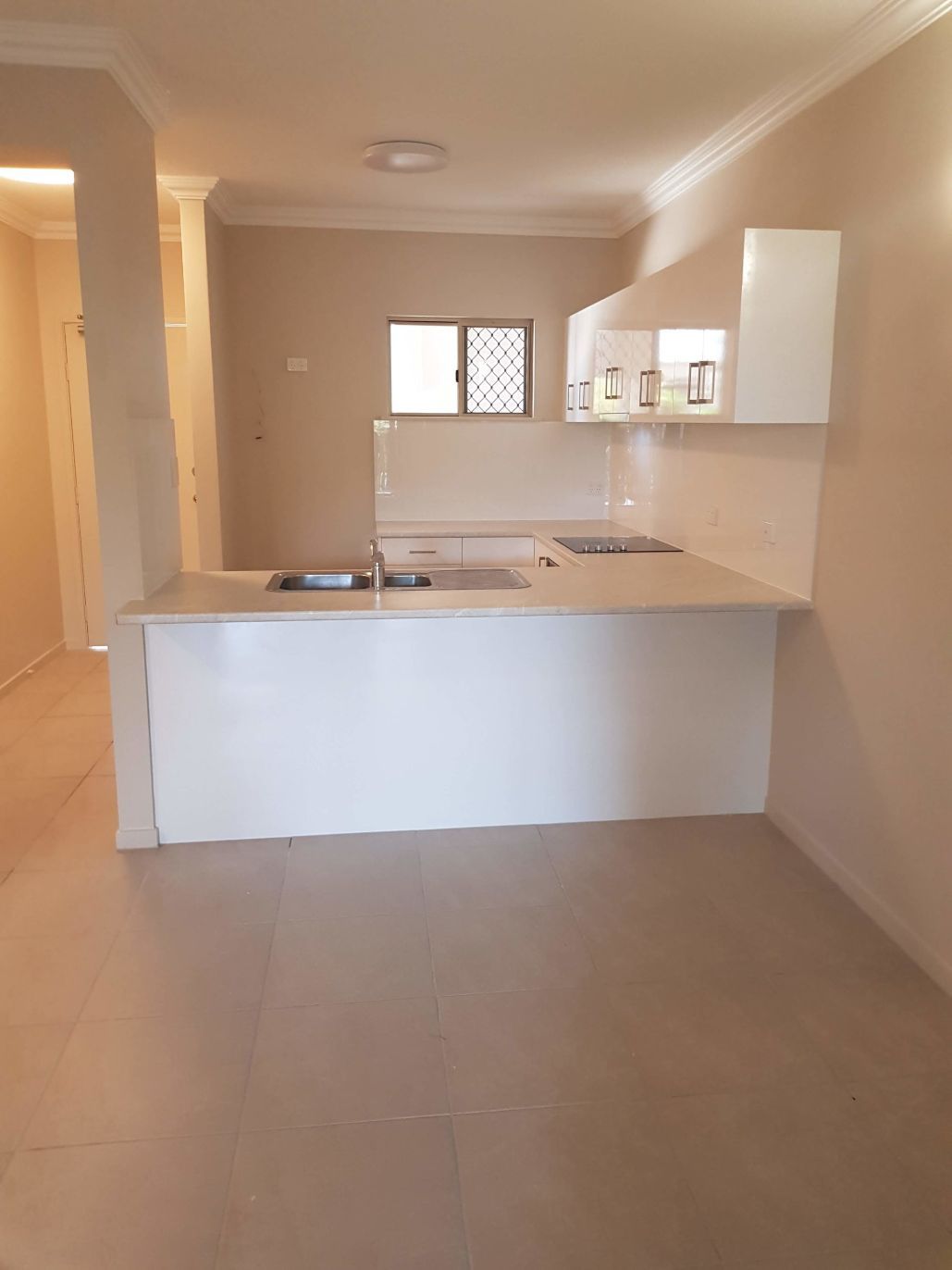 An Empty Kitchen With White Cabinets and a Sink — Omni Builders In Bungalow, QLD